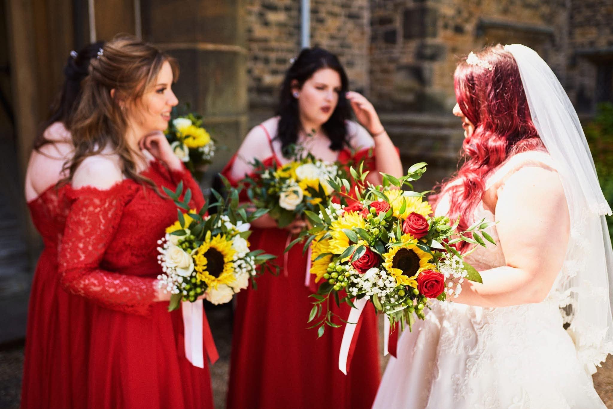 Bride and bridesmaids holding sunflower and rose bouquets