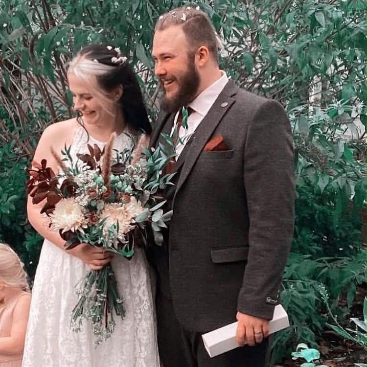 Newlyweds with a natural foliage-rich bridal bouquet